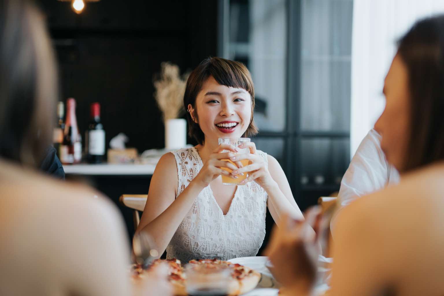 Women friends in their 20s enjoy pizza and cocktails at a restaurant