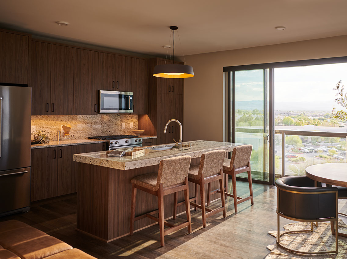 photo of kitchen with granite counter top, stainless steel appliances and counter stools